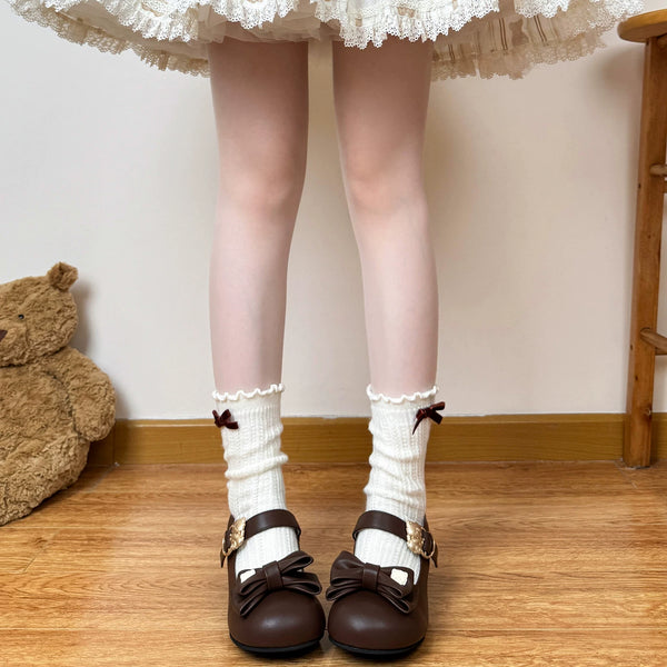 Cream knit scrunch socks with lace cuffs and ribbon bows styled with brown Mary Jane shoes