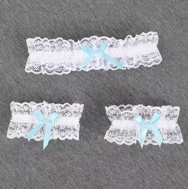 White lace leg garters with blue bows and scalloped trim on a gray background.
