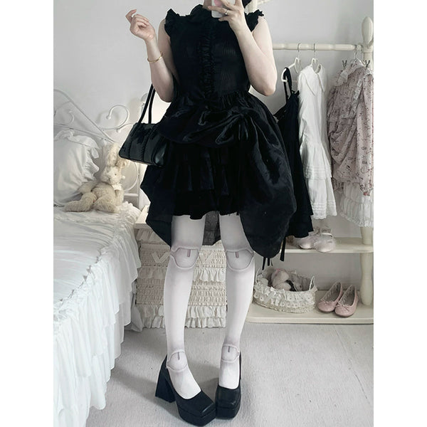 Model in a black frilled dress wearing pale tights and black platform shoes