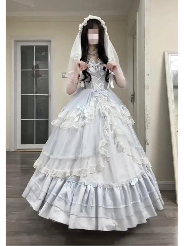 Model wearing a pale blue layered princess dress with bows and a white veil indoors.