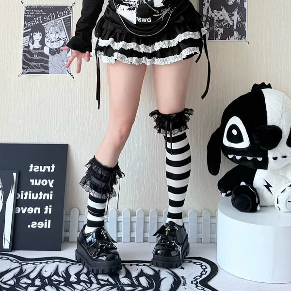 Black-and-white striped over-the-knee socks with gathered cuffs styled with a black outfit