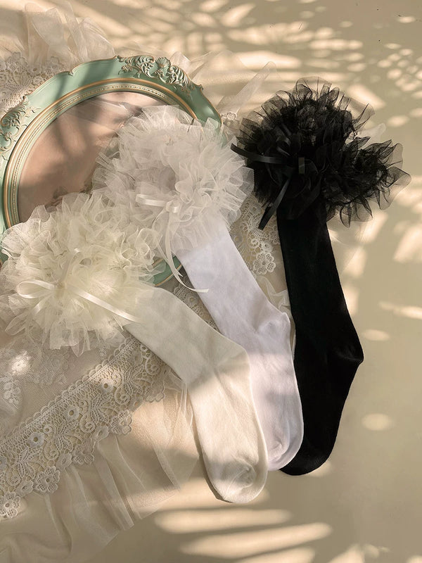 White ruffled mid-calf socks with floral lace cuffs styled with black Mary Jane shoes.