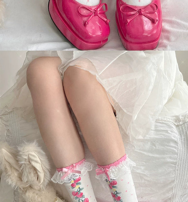 Short white strawberry-print socks with lace cuffs and ribbon bows, styled with red Mary Jane shoes.