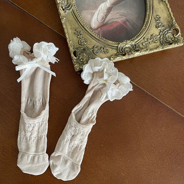 White layered tights and lace socks with ribbon bows and delicate trim.