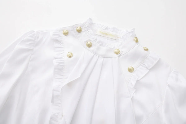 White Ouji blouse close-up with metallic buttons and ruffled front