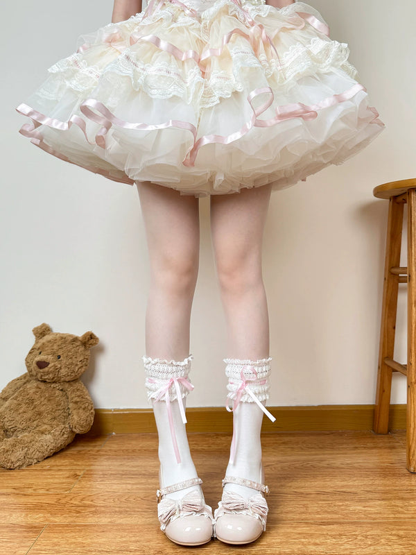 White lace-trim socks with pink ribbon accents styled beneath a layered skirt.