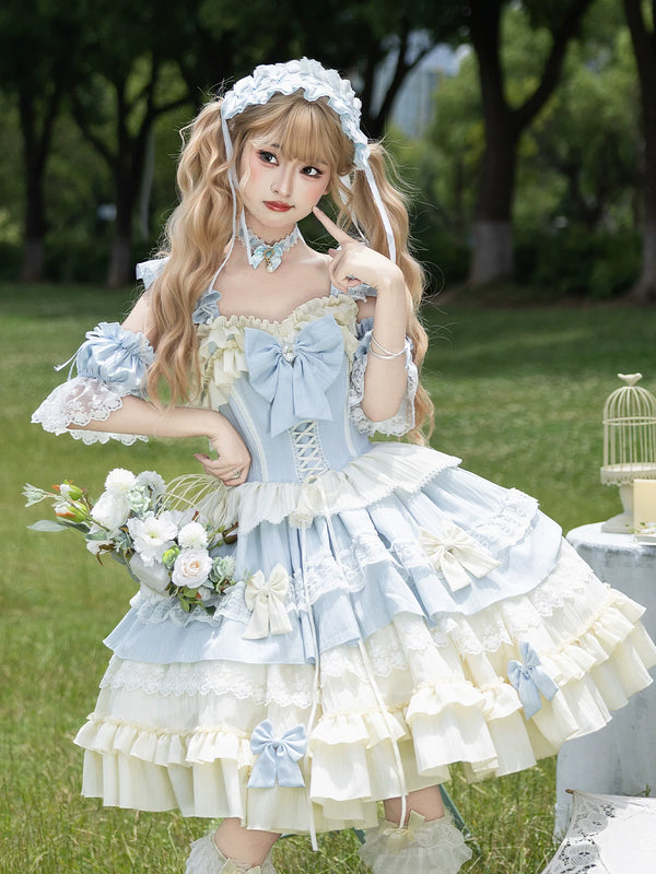 Model wearing full ice blue Sweet Lolita JSK set with matching accessories in a garden setting