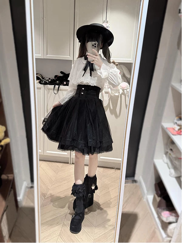 Model wearing a black-and-white cape blouse and short skirt in a mirror selfie.