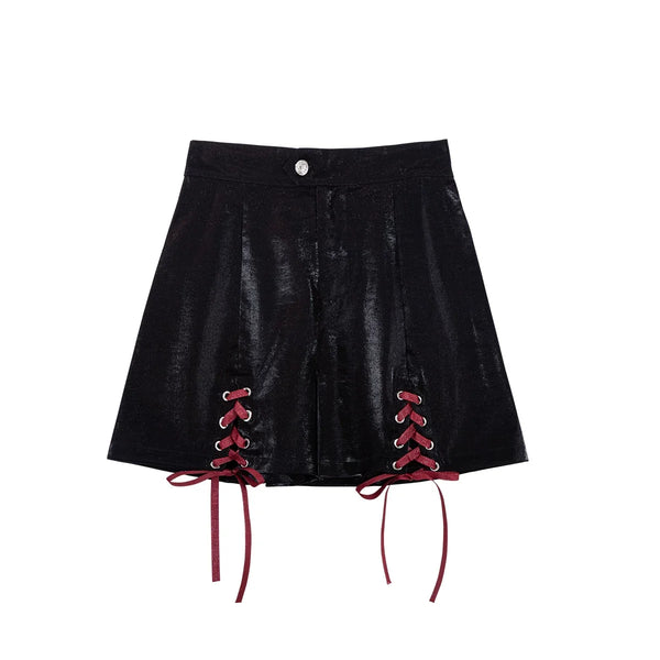 Black lace-up shorts and burgundy arm sleeves with buckle details.