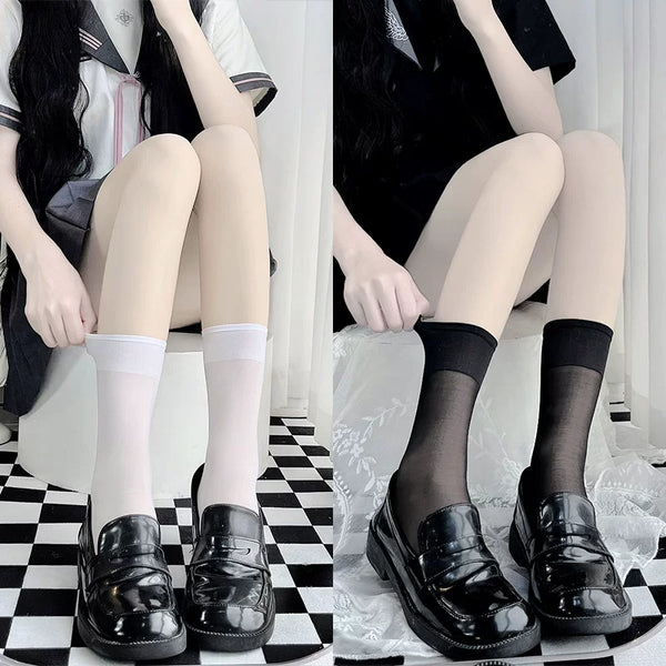 White and black sheer mid-calf socks styled with glossy black loafers.