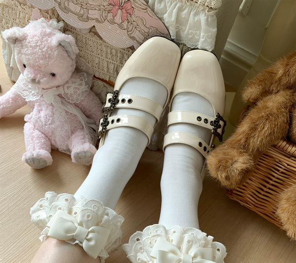 Lace-trimmed socks with bows in multiple colours arranged beside red shoes on a wooden floor.