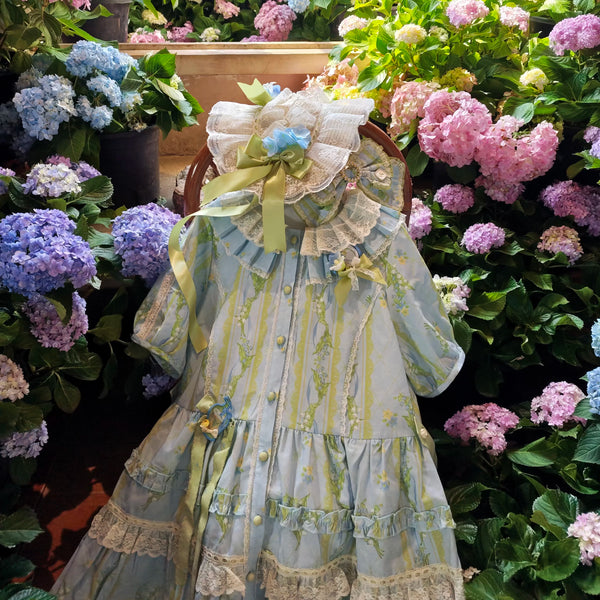 Blue floral Lolita dress with lace ruffles, ribbons and flower accents shown in a garden setting and on a mannequin.