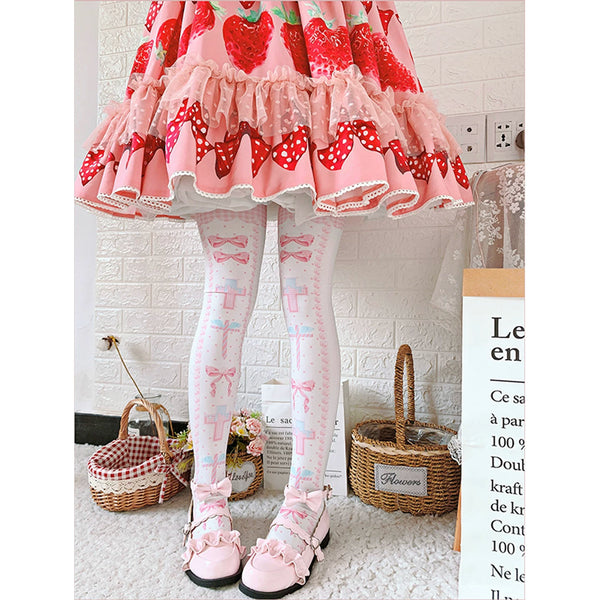 Model wearing printed over-the-knee socks with pink bows and cross motifs beneath a red-and-green skirt.