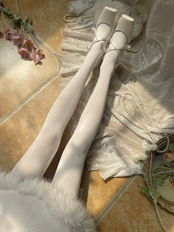 White cotton tights with fine vertical ribs styled with white Mary Jane shoes.