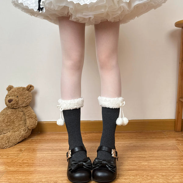 White scrunched mid-calf socks with fuzzy cuffs and dangling pom-poms