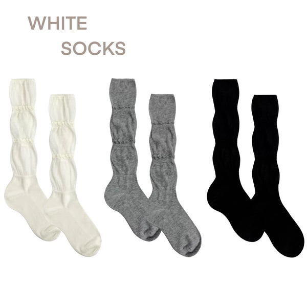 White, grey and black slouch socks with gathered ruffle bands on a white background.
