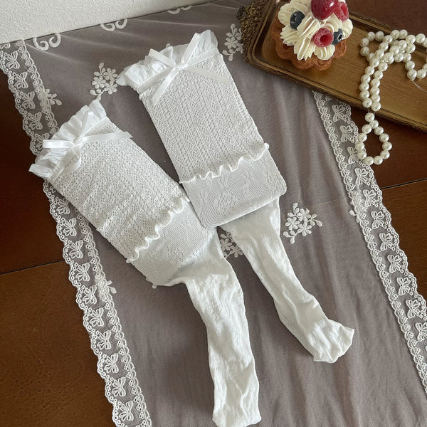 White lace stockings and legwear pieces with ribbon ties arranged flat on lace cloth.