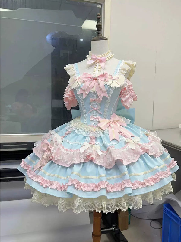 Blue-and-pink JSK dress with layered lace, bows and a full skirt displayed on a mannequin.
