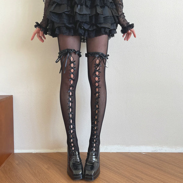 Black openwork tights with satin trim and bow-laced openings styled with platform shoes