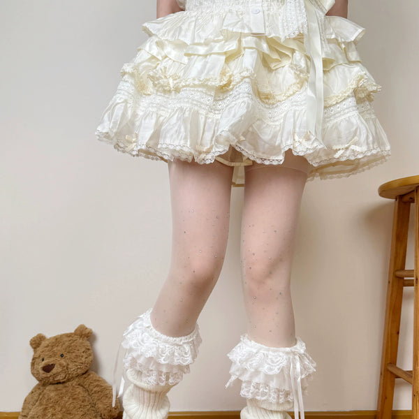 Milky white tights with scattered sparkle and bow details styled beneath a ruffled white skirt.