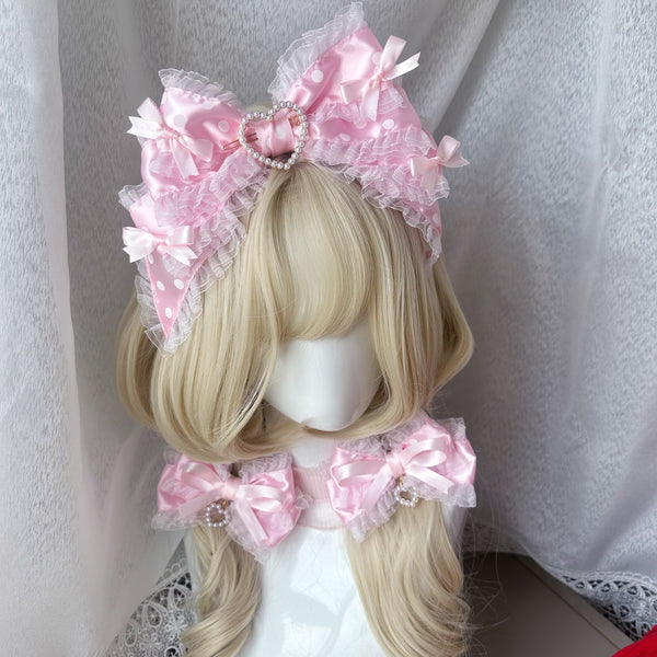 Pink polka-dot bow headband with pearl-edged heart detail on blonde hair.