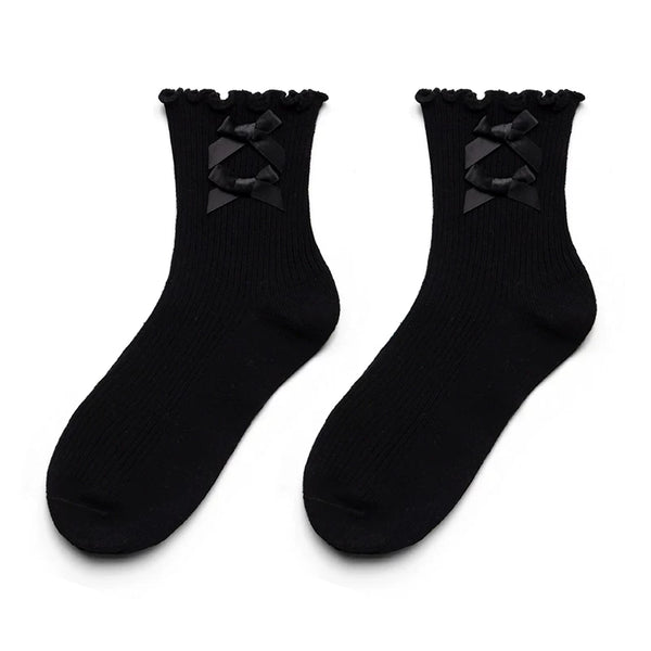 White cotton short socks with bow and ruffle details shown with white shoes.