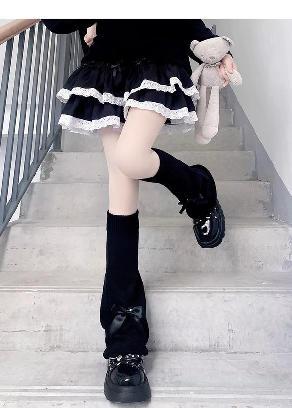 White bow and plain knit calf sock covers styled with black platform shoes on models.