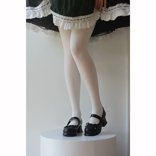 White pantyhose styled under a dark lace-trimmed skirt with Mary Jane shoes.