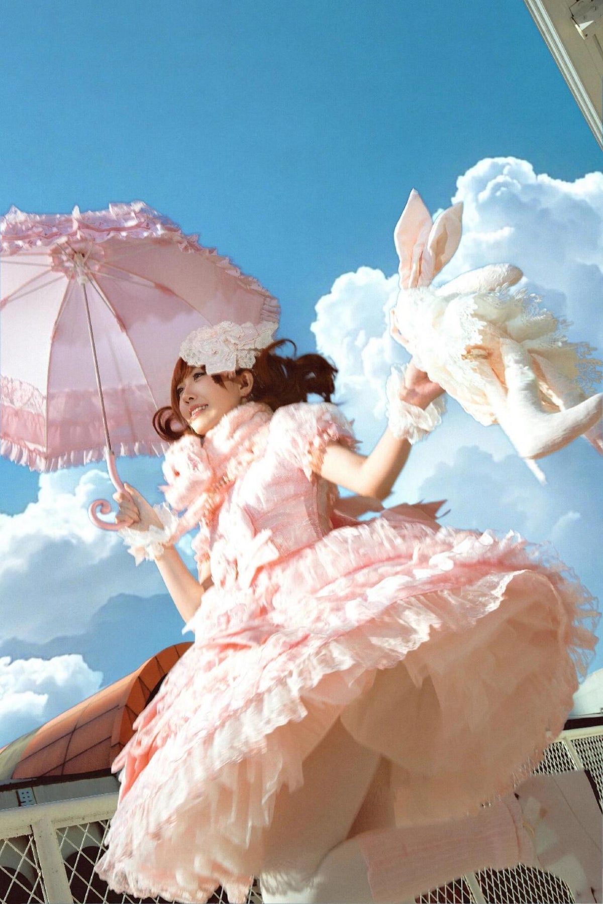 Pink Lolita dress and parasol photographed against a blue sky