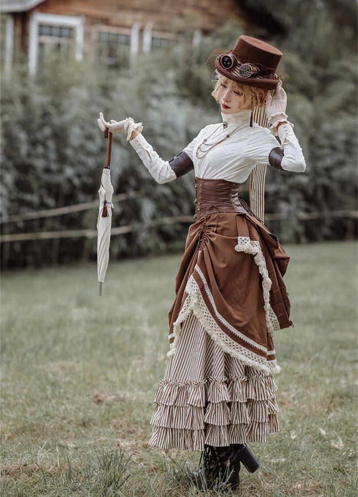Full-length brown and ivory steampunk coordinate with a small hat and pale parasol outdoors