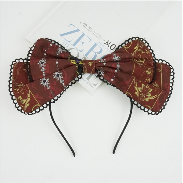 Wine-red bow KC headband with black scalloped lace edging laid flat.