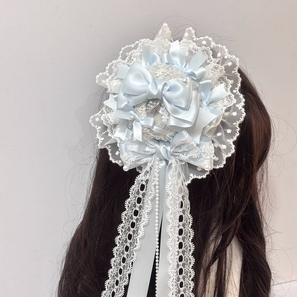 Pale blue mini top hat with layered bows, lace, pearls and a trailing veil worn in the hair.