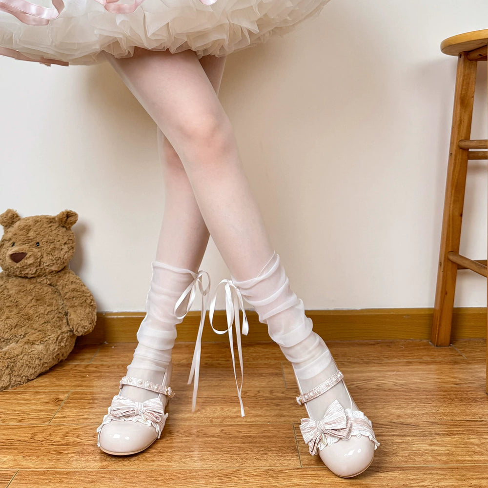 White sheer mid-calf socks with long ribbon bows beneath a layered skirt