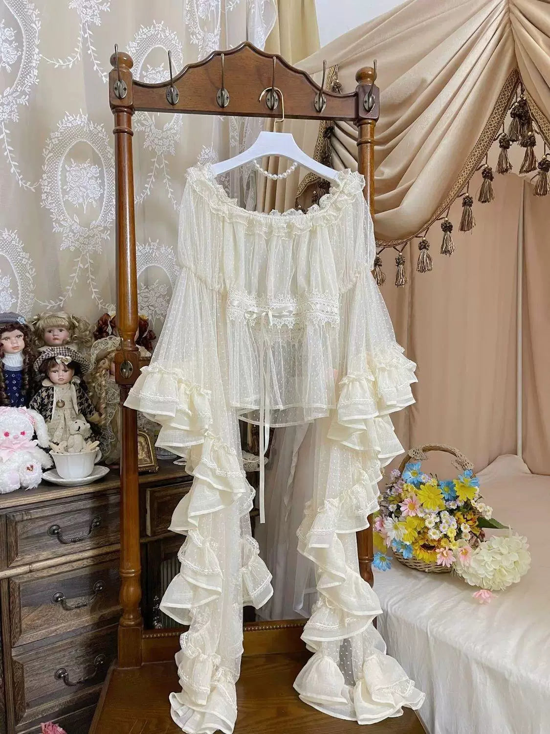White off-shoulder Lolita Blouse with sheer dotted mesh sleeves and layered ruffled trim on a wooden hanger.