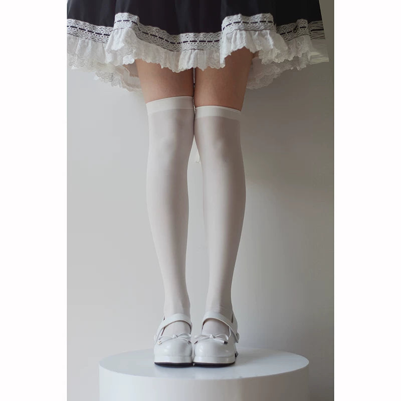 Model wearing white velvet over-the-knee socks with a dark ruffled skirt and white shoes.