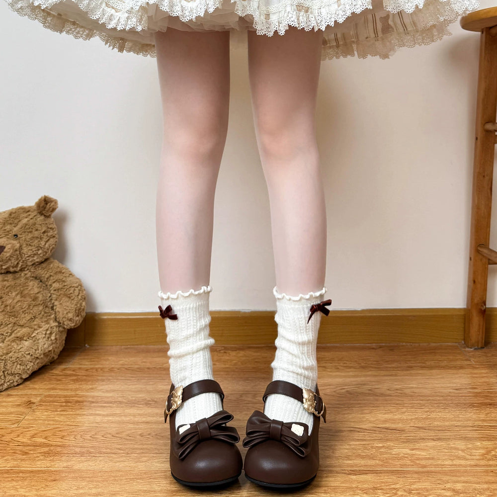 Cream knit scrunch socks with lace cuffs and ribbon bows styled with brown Mary Jane shoes