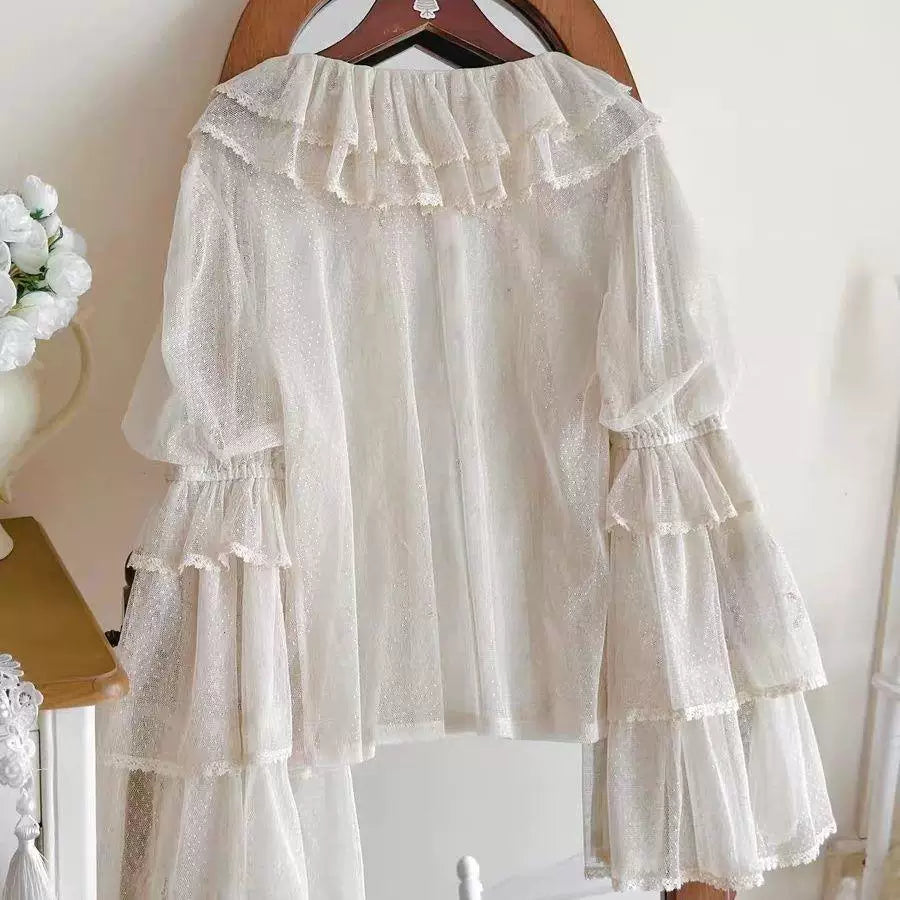 White dotted-mesh long-sleeve inner top on a hanger with a ruffled collar and tiered sleeves.