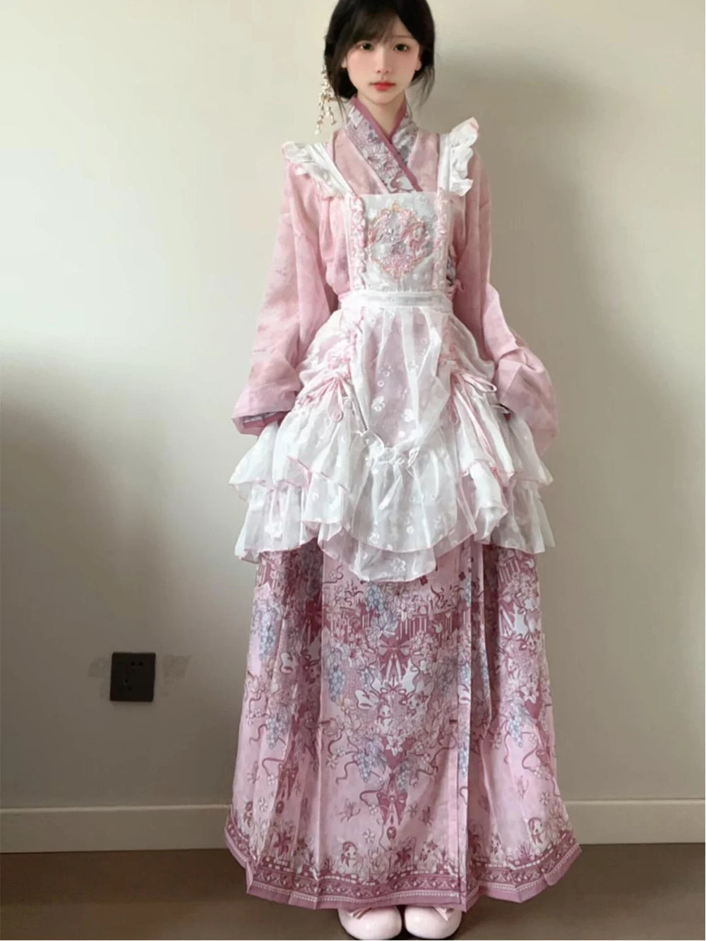 Model wearing a pink Hanfu-inspired Lolita fashion set with a patterned skirt and ruffled overlay.