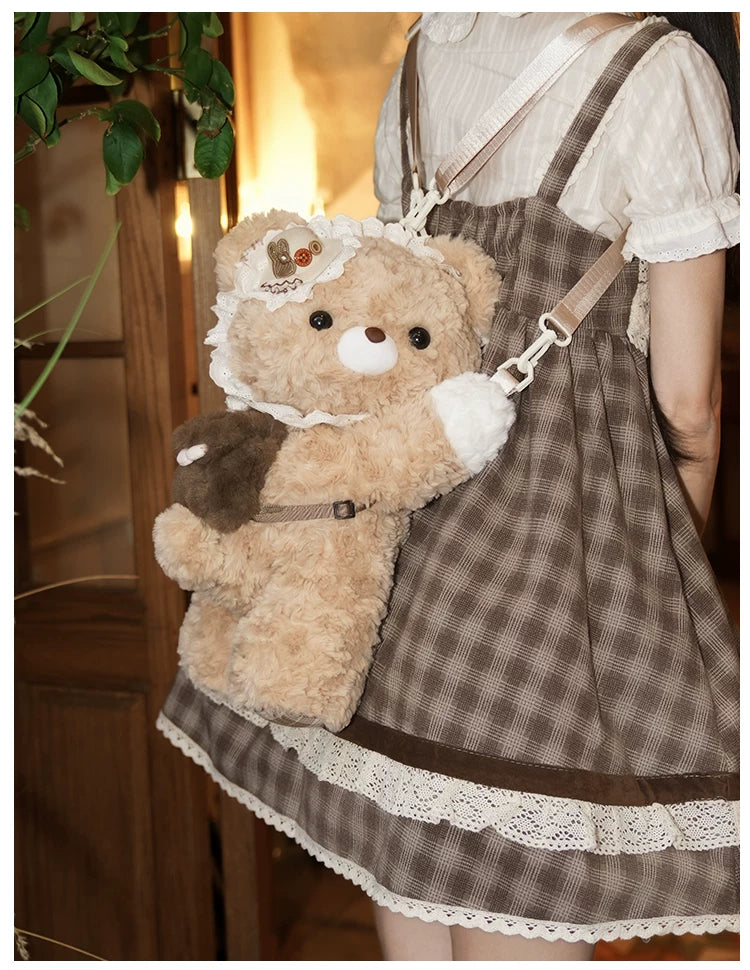 Tan plush bear crossbody bag with a lace collar and small front pouch.