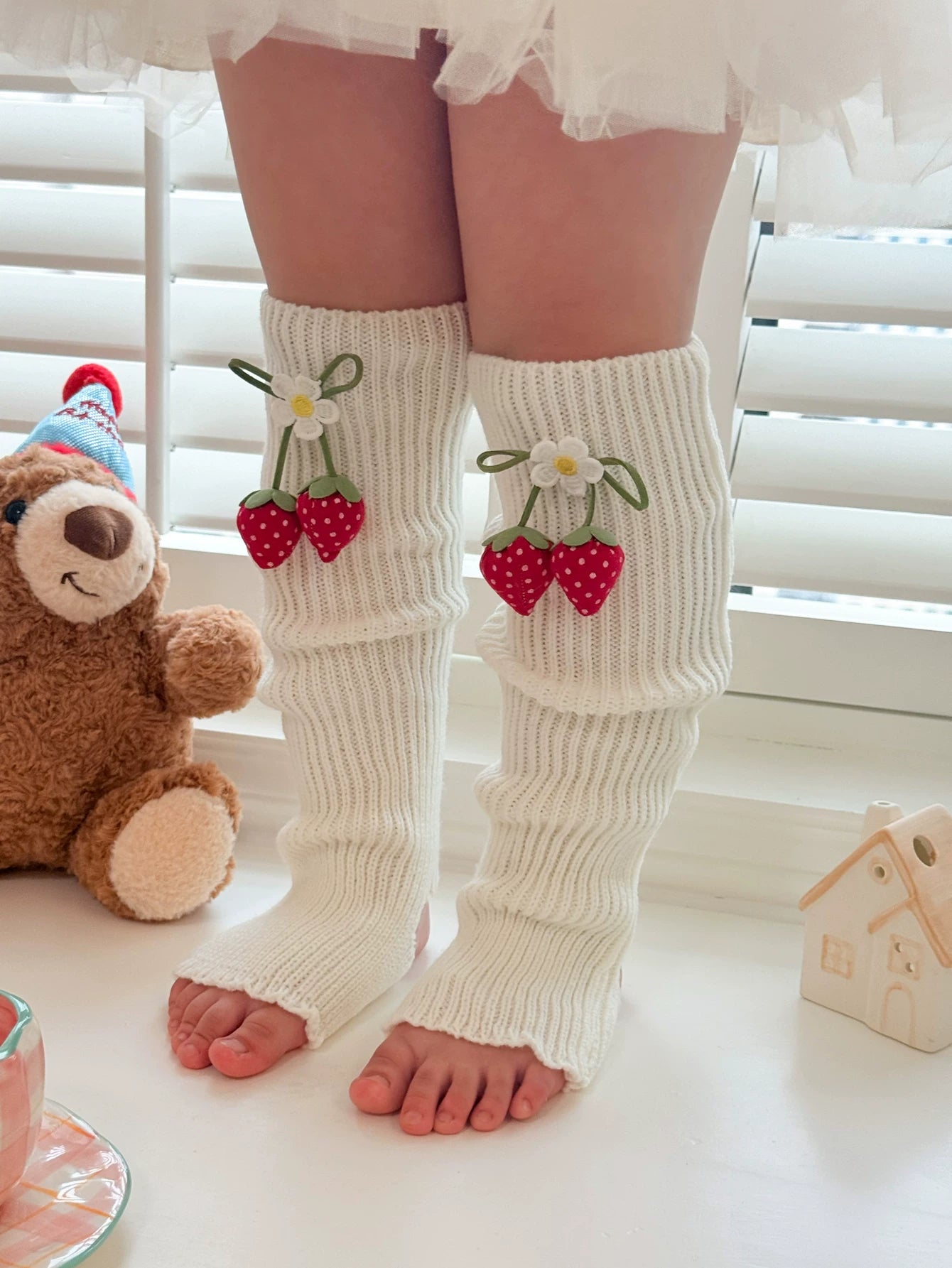 White lace socks and strawberry-decorated stirrup sock covers shown in close-up.