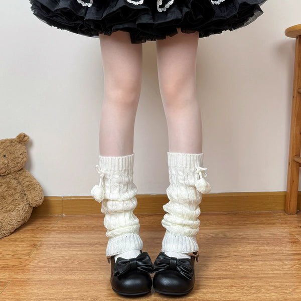 White cable-knit sock leg warmers with pom-pom ties styled with black shoes