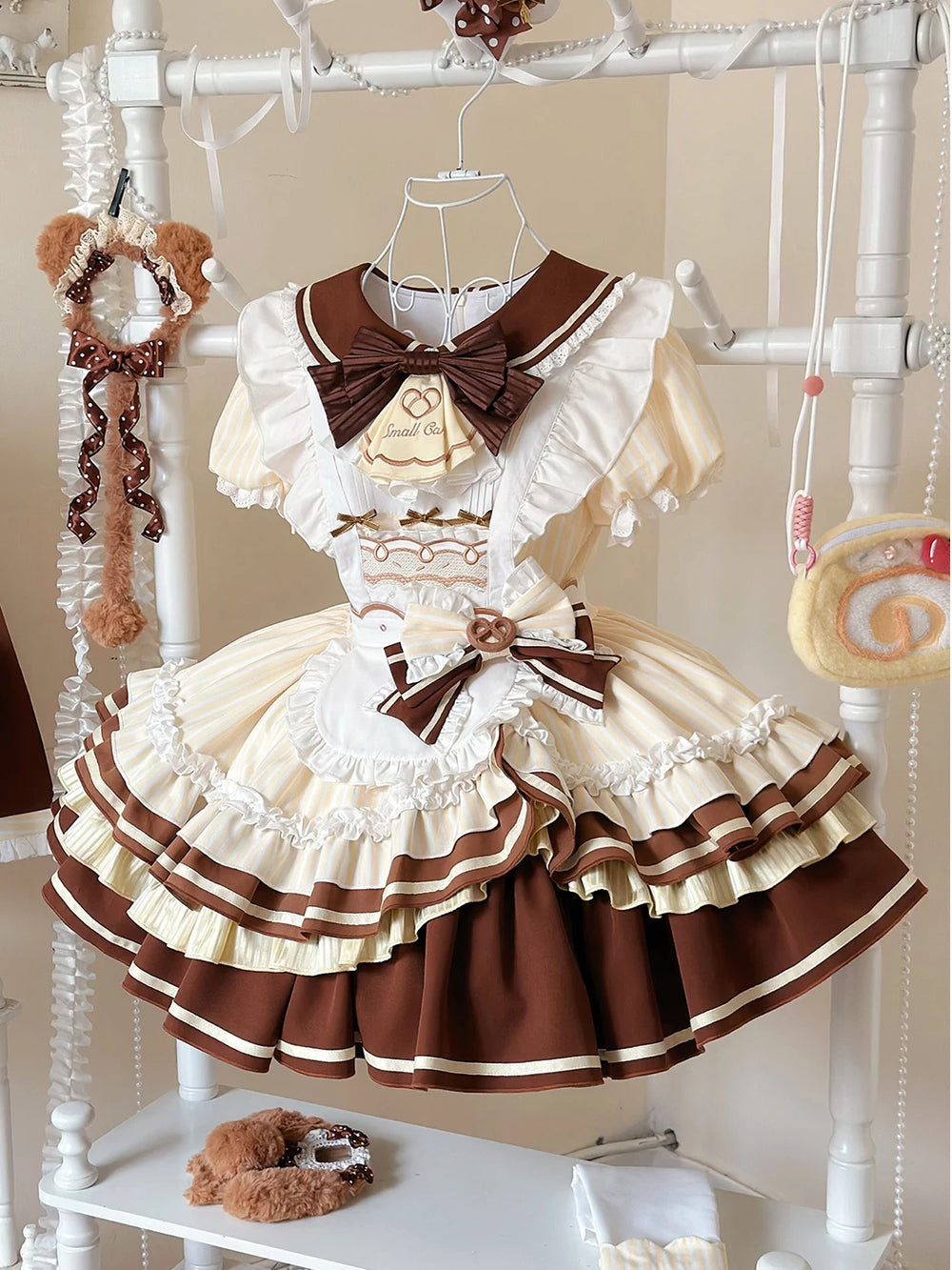 Cream-yellow and chocolate one-piece dress with apron, bows and large back train on a hanger