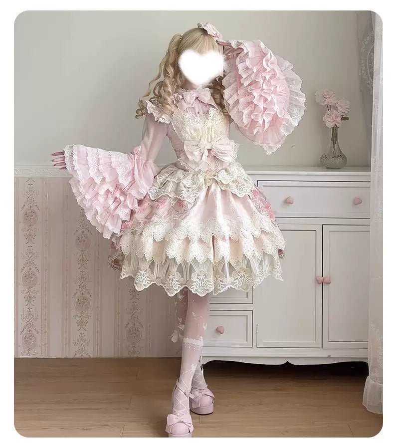 Pink long-sleeve blouse with bow bib and wide lace-trimmed flared cuffs displayed flat.