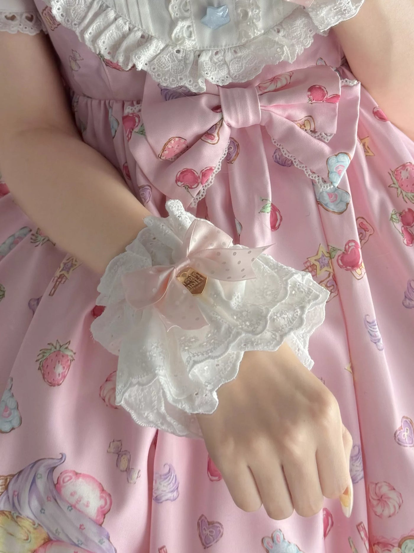 Pink lace hand sleeves with ribbon bows worn with a pink printed Lolita dress.