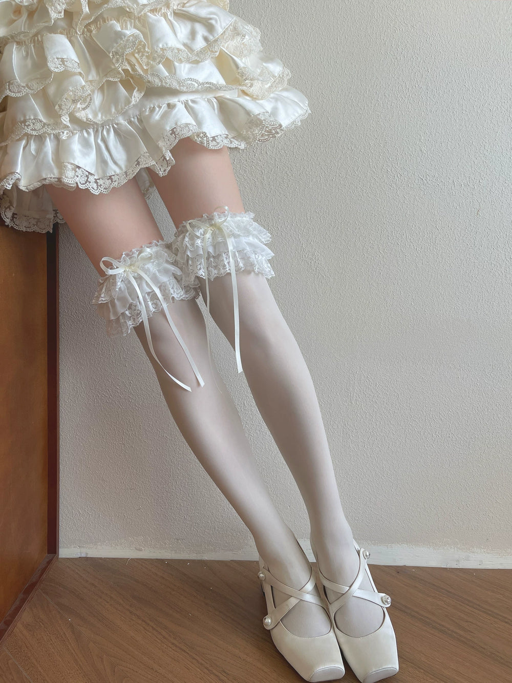 White Lolita socks with layered lace ruffles and bow ribbons styled on the legs