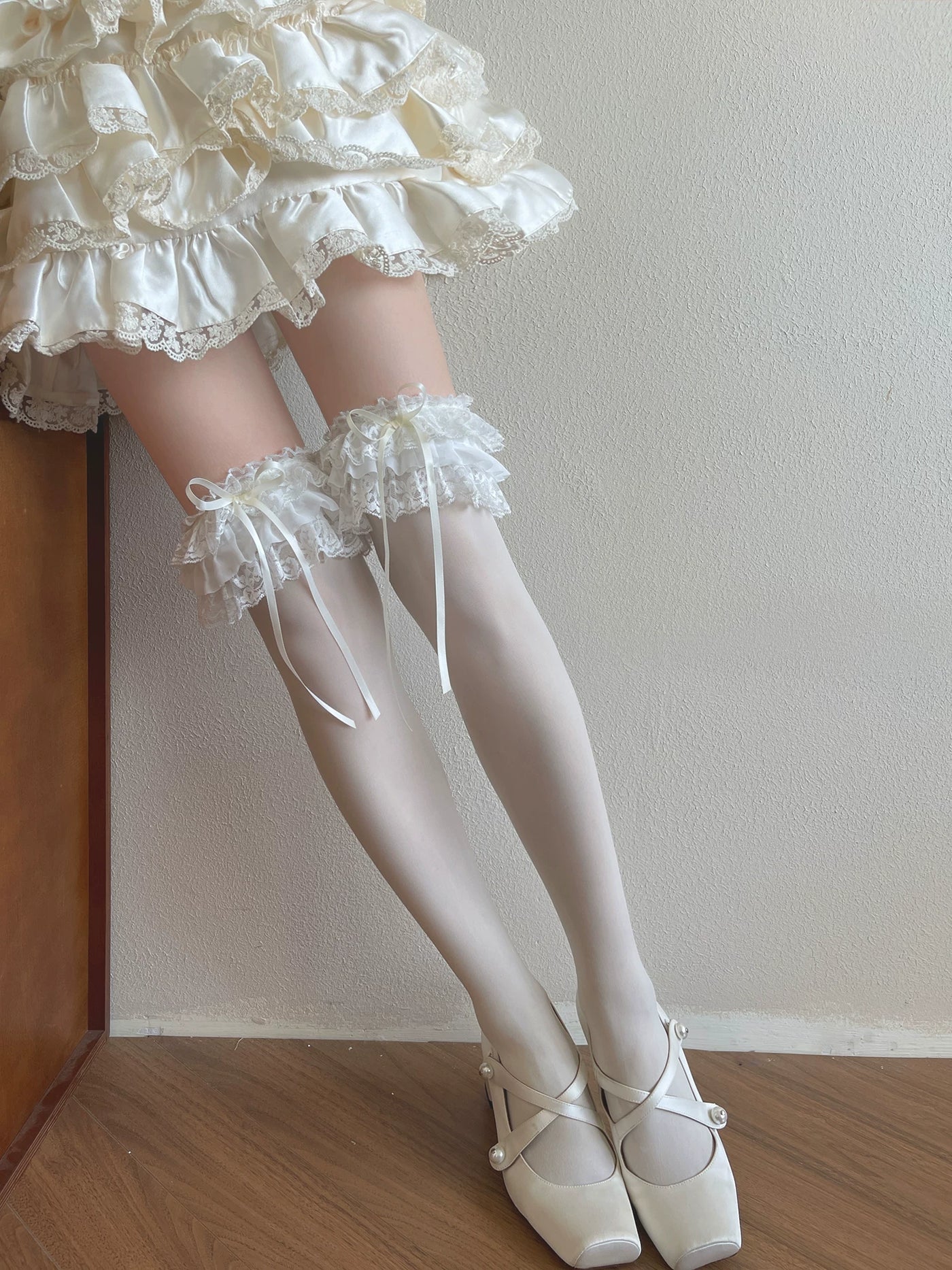 White Lolita socks with layered lace ruffles and bow ribbons styled on the legs