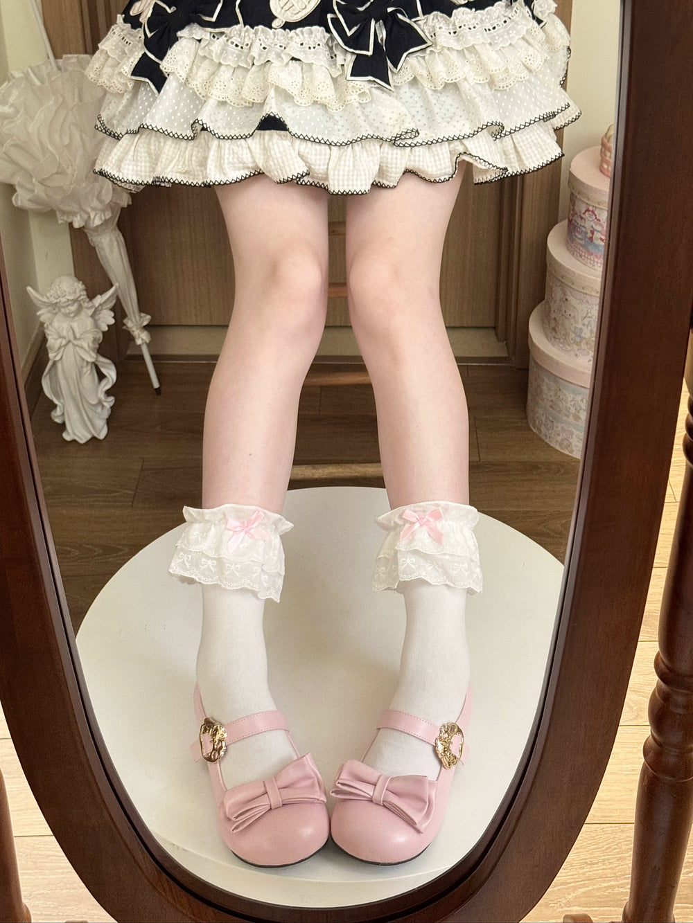 White mid-calf socks with layered lace cuffs and pink bows styled with pink Mary Jane shoes.