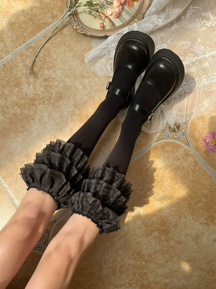 Black and white three-tier lace ruffle socks worn with black strap shoes.