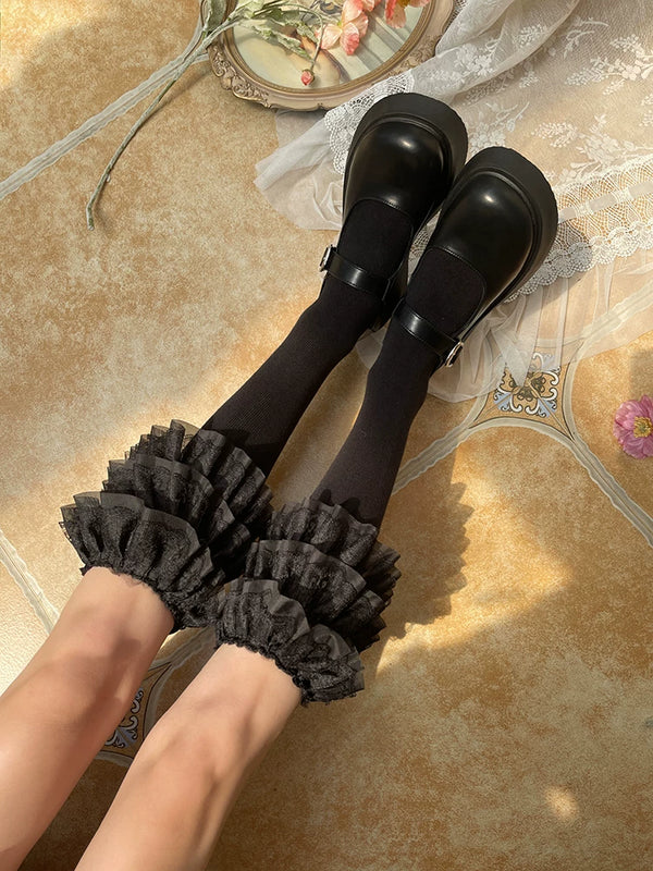 Black and white three-tier lace ruffle socks worn with black strap shoes.