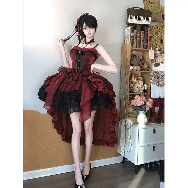 Model wearing a deep red JSK dress with black ruffles, rose accents and a large train.